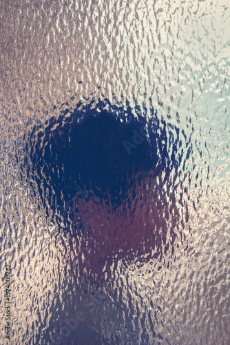 Abstract blurred silhouette of child head behind textured glass suggesting emotion, neurodivergence, perception, and mental health themes for psychology, therapy, and education uses. Vertical image.
