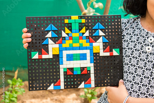 Girl child hand holding magnetic board game having robot design solved.
