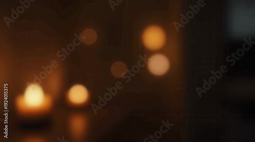 A blurred warm indoor scene featuring a glowing candle in the foreground and golden light circles in a dark cozy room 
