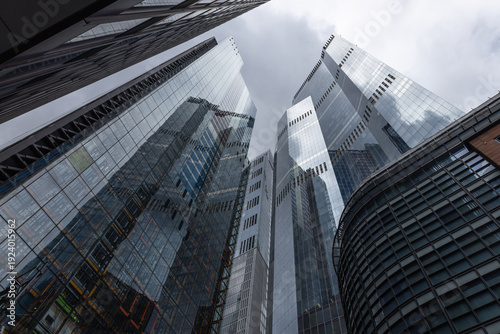Schilderij op canvas Modern glass skyscrapers reaching towards a cloudy sky