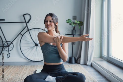 Tableau sur toile A young woman performs stretching movements in a comfortable living room, improv