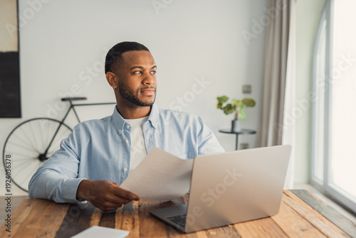 Photography An African American professional gazes out the window while holding business doc