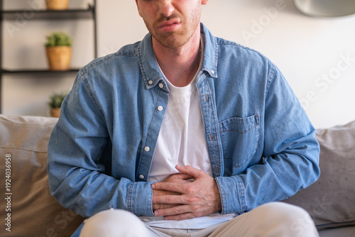 Foto Sick young man in pain holding belly stomach feeling hurt abdomen ache gastritis