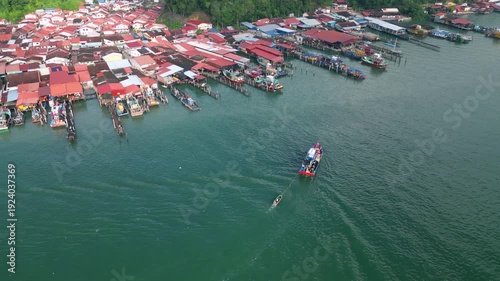Aerial perspective captures Pulau Pangkor, fisherman boat moving steadily across shimmering waters near coastal village.