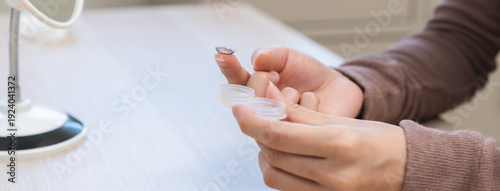 Foto Ophthalmology care, eye sight, vision concept, asian young woman, girl hand holding eye lens and putting soft contact lenses on her finger from box case on table at home