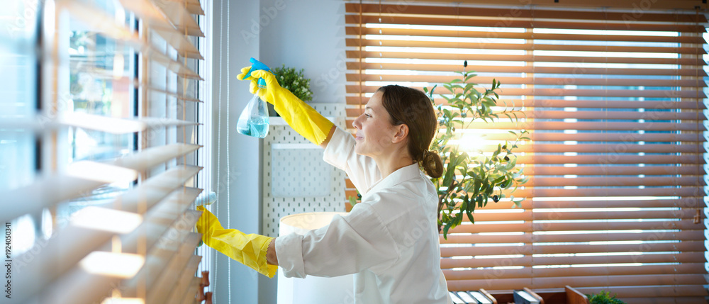 © Stella 16 - A woman cleans window blinds at home with a rag and gloves, focusing on dust removal, hygiene, household chores, tidiness, daily maintenance, and creating a neat living environment © Stella 16 - A woman cleans window blinds at home with a rag and gloves, focusing on dust removal, hygiene, household chores, tidiness, daily maintenance, and creating a neat living environment