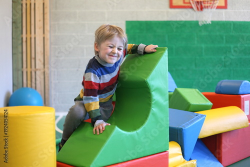 Young Child Climbing Soft Play Blocks in Indoor Gym, Colorful Preschool Activity Area. Toddler playing at playdroud
