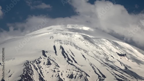 Time lapse clouds swirl around snowy summit of Mount Kilimanjaro, Africa highest peak. Fast motion vapor streams hug ice capped volcano crest, revealing dramatic sky shifts above Tanzania.