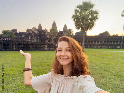 Happy Woman Taking Selfie and Pointing at Angkor Wat Temple in Cambodia