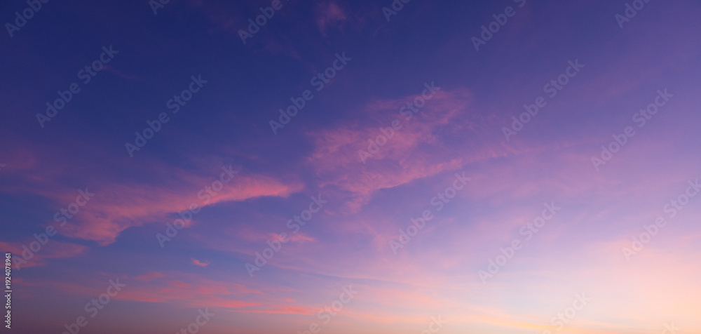 Obraz premium Beautiful sunset sky with orange and blue gradient clouds background,A stunning panoramic view of the twilight sky during sunset, featuring a vibrant gradient of deep blue, purple, and golden orange 