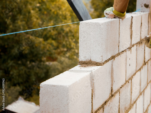 Foto A skilled worker meticulously lays concrete bricks to build a sturdy wall for a new home
