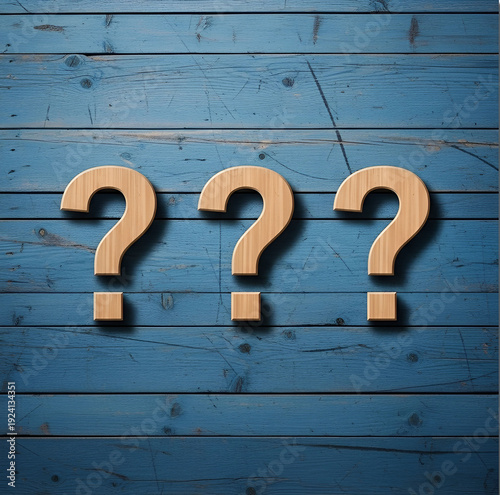 Three wooden question marks on blue painted wooden planks background with visible texture