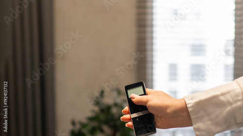 Bild auf Leinwand a woman holds in her hand a remote control for an automatic roller shutter control system