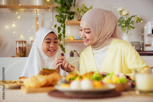 Muslim mother and daughter eating dates together at Ramadan iftar table