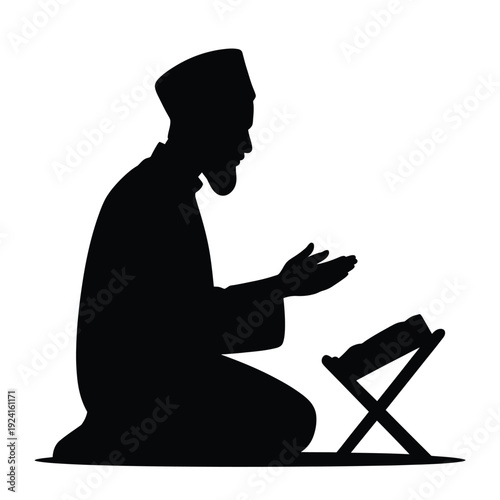 Silhouette of a muslim man kneeling reading from a book on a stand in prayer