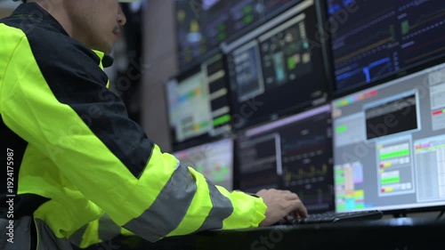 Professional engineer monitoring complex data systems on multiple screens in modern control center. Male worker analyzing digital charts and graphs for security and automation performance.