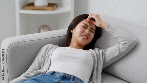 Young woman reclining on a gray couch in a relaxed pose at home