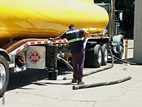 Картината върху платно Driver in yellow vest watches process of off loading diesel fuel at customer facility, with hazmat placard