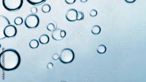 Forming along bottom, cluster of bubbles rising due to buoyancy in clear liquid with dark rims