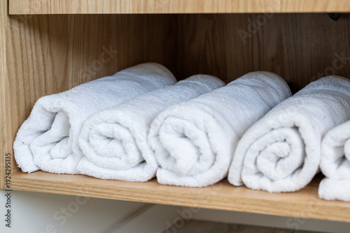 Minimalist Bathroom Interior with White Towels rolled up on shelf