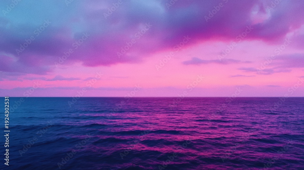 Obraz premium A tranquil ocean at sunset with a vibrant purple and pink sky reflecting on calm waters.