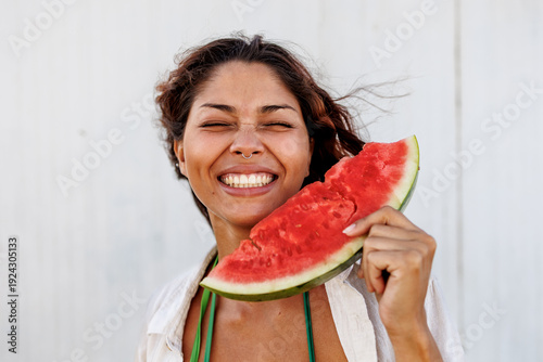 Young woman smiling while holding a large slice of fresh watermelon