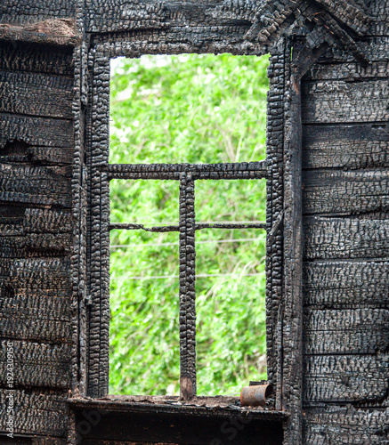 Charred wooden window frame of a burned down house. Burnt broken wood wall