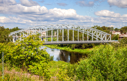 View on the steel arch bridge across the Msta river in summer. Built in 1905. Borovichi, Russia