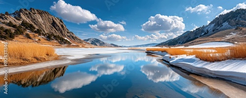 Panel kuchenny z motywem Wide alpine lake landscape with melting snow, golden grasses, and snowy mountains under a blue sky