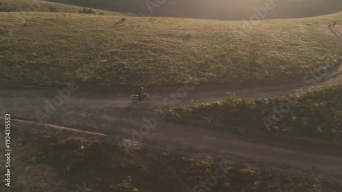 Vista aérea de uma mulher pilotando uma motocicleta em uma estrada de terra no alto da montanha