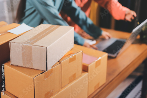 Startup SME small business entrepreneur of freelance Asian woman wearing apron using laptop and box to receive and review orders online to prepare to pack sell to customers, online sme business ideas.