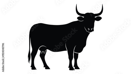 Silhouette of a bull with long curved horns standing in a profile view
