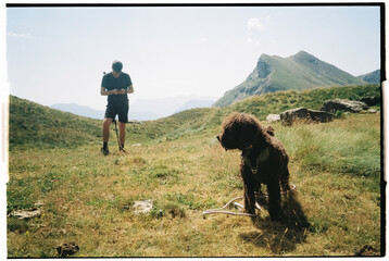 Film photo of a person and a dog on a mountain hike