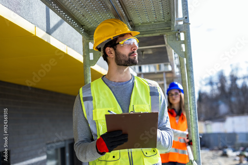 Male and female engineers performing a safety inspection on construction scaffolding.