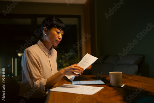 Asian woman working late night reading documents at home