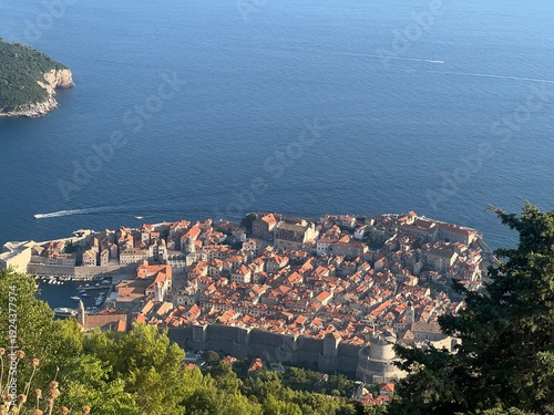 Mountain side bird's view of Dubrovnik Old Town, city walls, red roofs, green trees in front, Adriatic sea in back, on a sunny august summer day, Dubrovnik, Croatia
