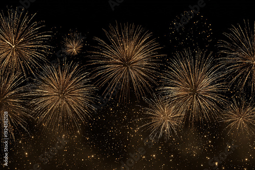 Dazzling golden fireworks burst against a dark night sky creating a festive and celebratory atmosphere with shimmering particles below