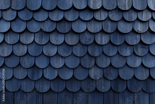 Dark blue wooden shingles arranged in a repeating scalloped pattern revealing wood grain texture