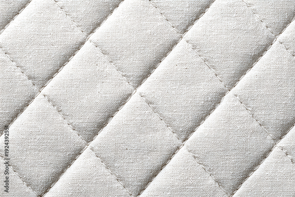 Obraz premium A close up textured view of light colored quilted fabric with diamond stitching