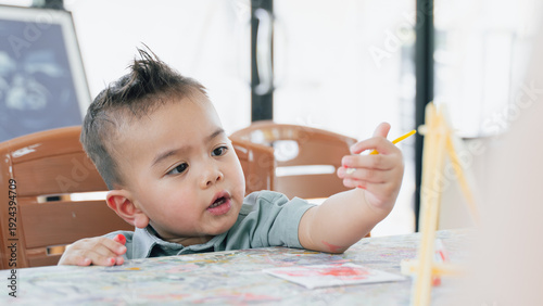 Cute Asian Toddler Boy Learning and Drawing at Home with Parent Support in Bright Living Room.