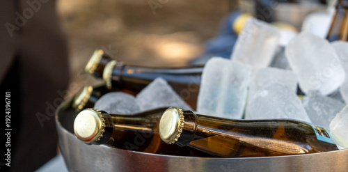 Chilled beer bottles resting in large ice-filled bucket at outdoor event
