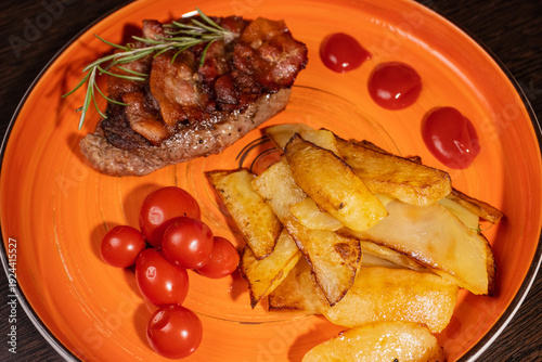 Steak with fried potatoes and tomatoes on a plate