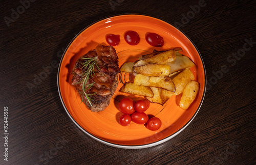 Steak with fried potatoes and tomatoes on a plate
