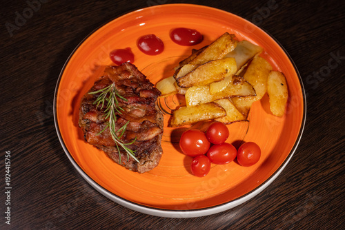 Steak with fried potatoes and tomatoes on a plate