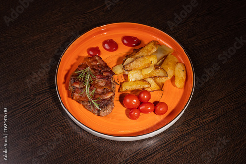 Steak with fried potatoes and tomatoes on a plate