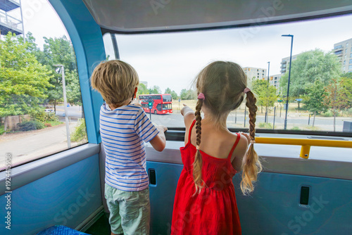 Foto Two kids excitedly point at a red imperial bus from upper deck