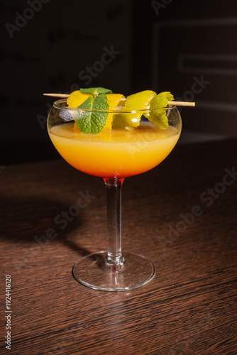 A alcoholic cocktail with orange juice is beautifully decorated by the bartender