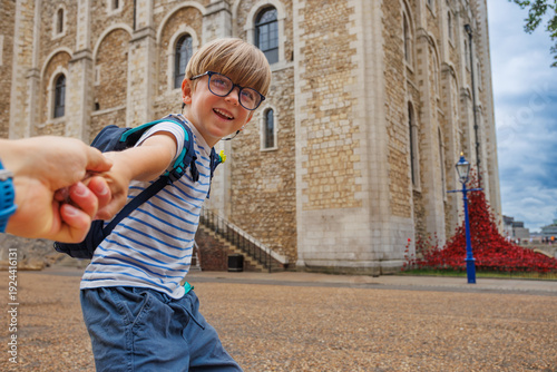 Happy kid boy joyfully holding adults hand at Tower of London