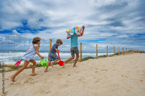 Kids racing to beach with toys and towels in summer vacations