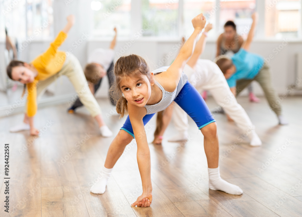 Fototapeta premium Group of children boys and girls with coach warming up before dance class in studio